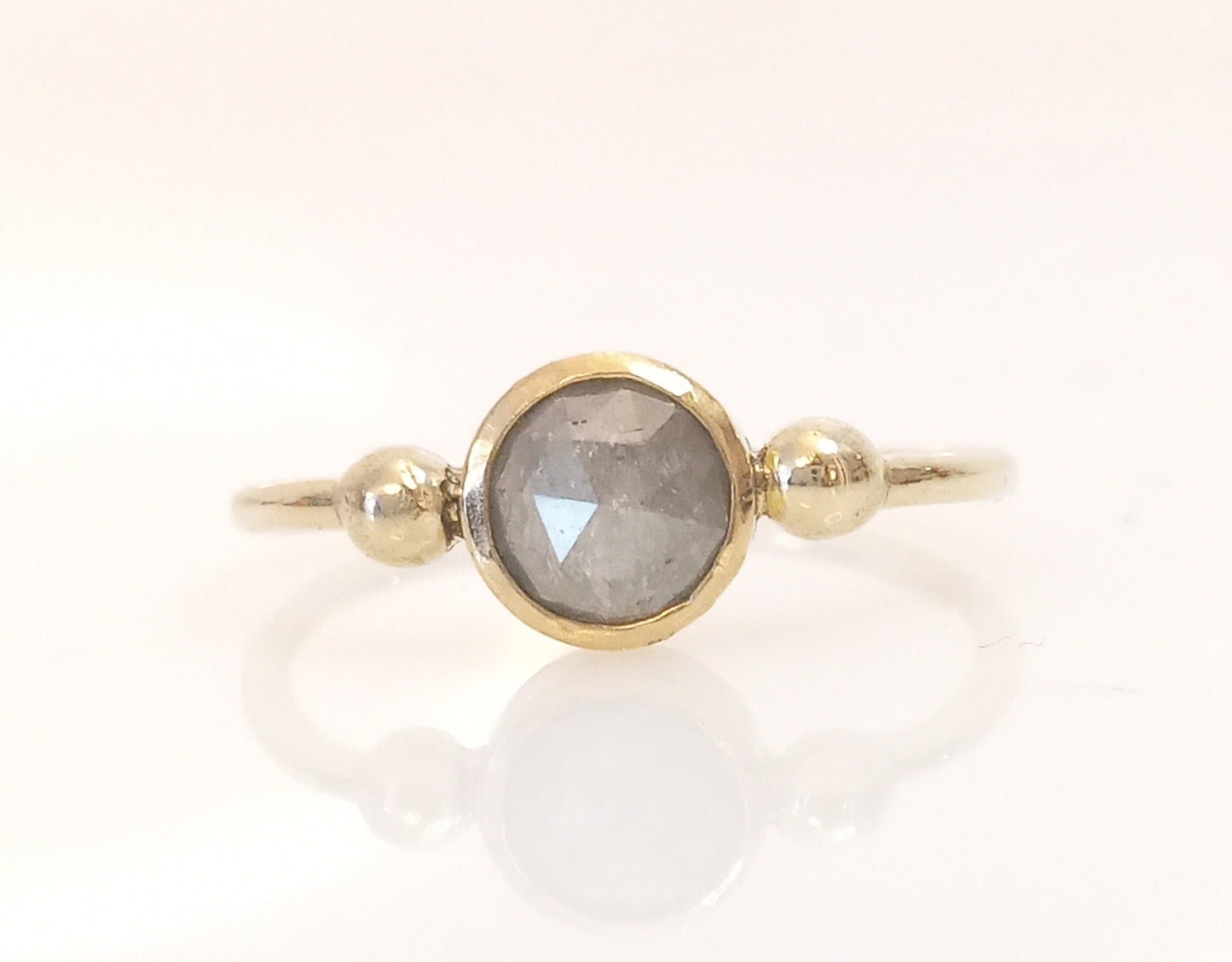 Ein runder silbergrauer Diamant im Rosenschliff, gefasst in 585er Gelbgold