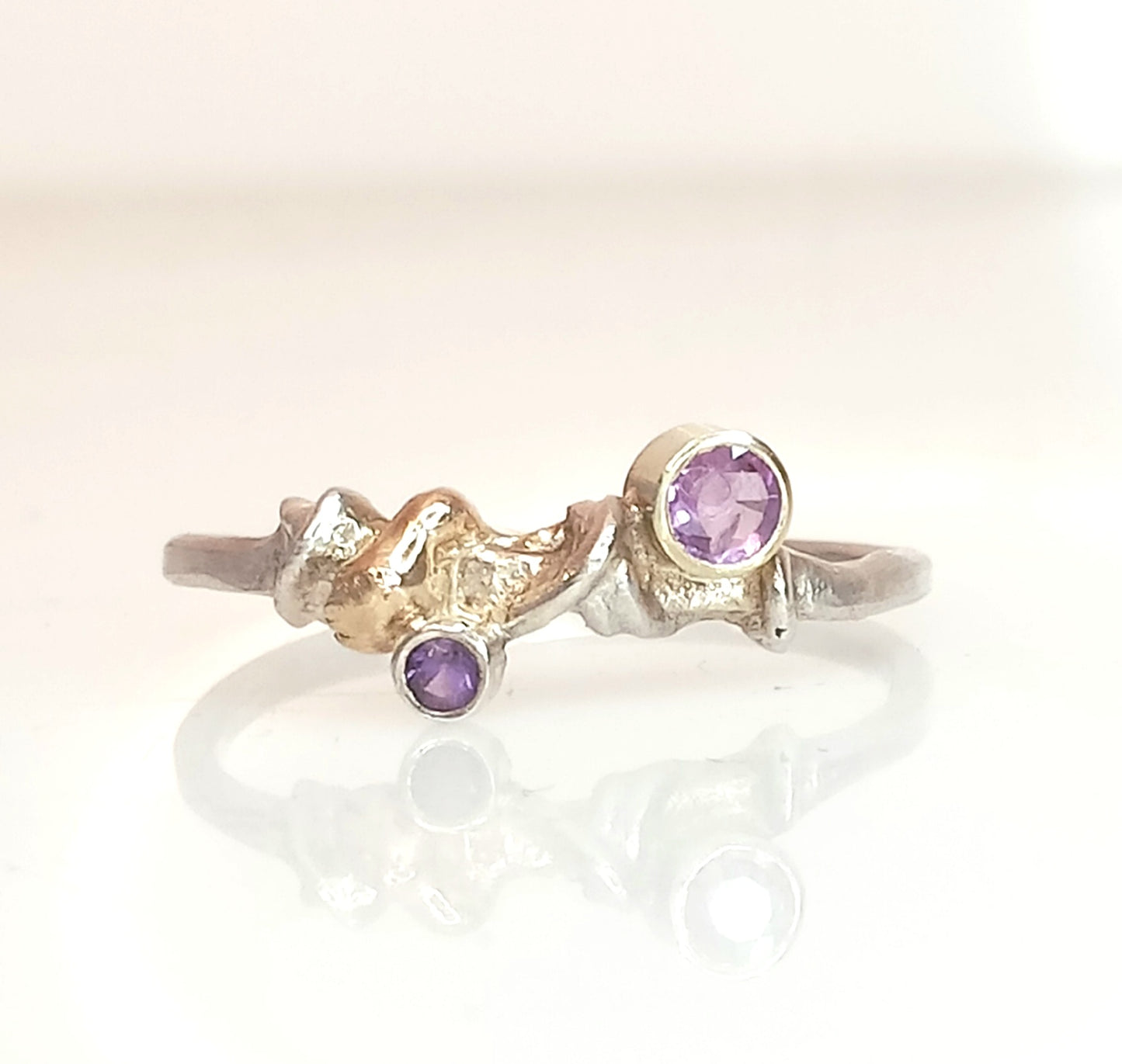 
                  
                    Handgefertigter Ring mit 3 mm rosa Saphir und 2 mm Amethyst auf 1,5 mm breitem Band aus recyceltem Silber, Saphir in 585er Gold gefasst, Ringgröße 56,5, Unikat-Schmuckstück aus der Überwachsen-Kollektion.
                  
                