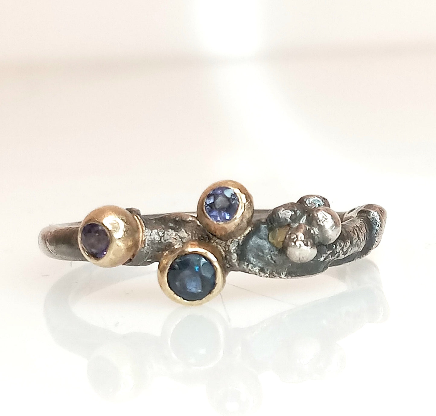 Handgefertigter Ring aus oxidiertem Silber mit Goldakzenten und drei Edelsteinen: einem blauen Saphir und zwei Iolithen in Lila und Lavendel, Ringgröße 56,5