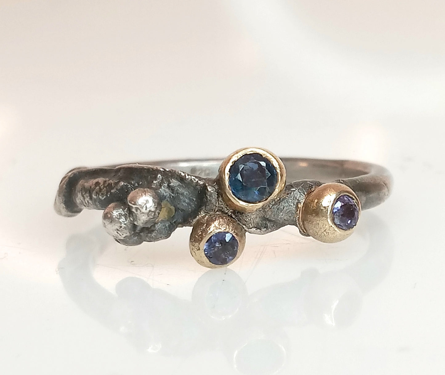 Oxidierter Silberring mit recyceltem Gold, besetzt mit blauem Saphir und zwei Iolithen in Lila und Lavendel, Ringgröße 56,5, handgefertigt.