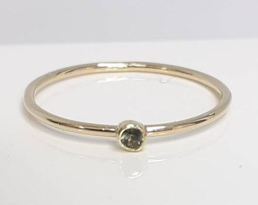 Ein zarter Ring aus 14-karätigem Gelbgold mit einem 2 mm großen, blassgrünen Saphir. Die Saphire stammen aus Australien und werden ethisch abgebaut. Perfekt als Verlobungsring, zum Stapeln mit anderen Ringen oder zum Tragen als sein eigenes süßes Selbst. Dieser Ring hat eine 1 mm breite Ringschiene