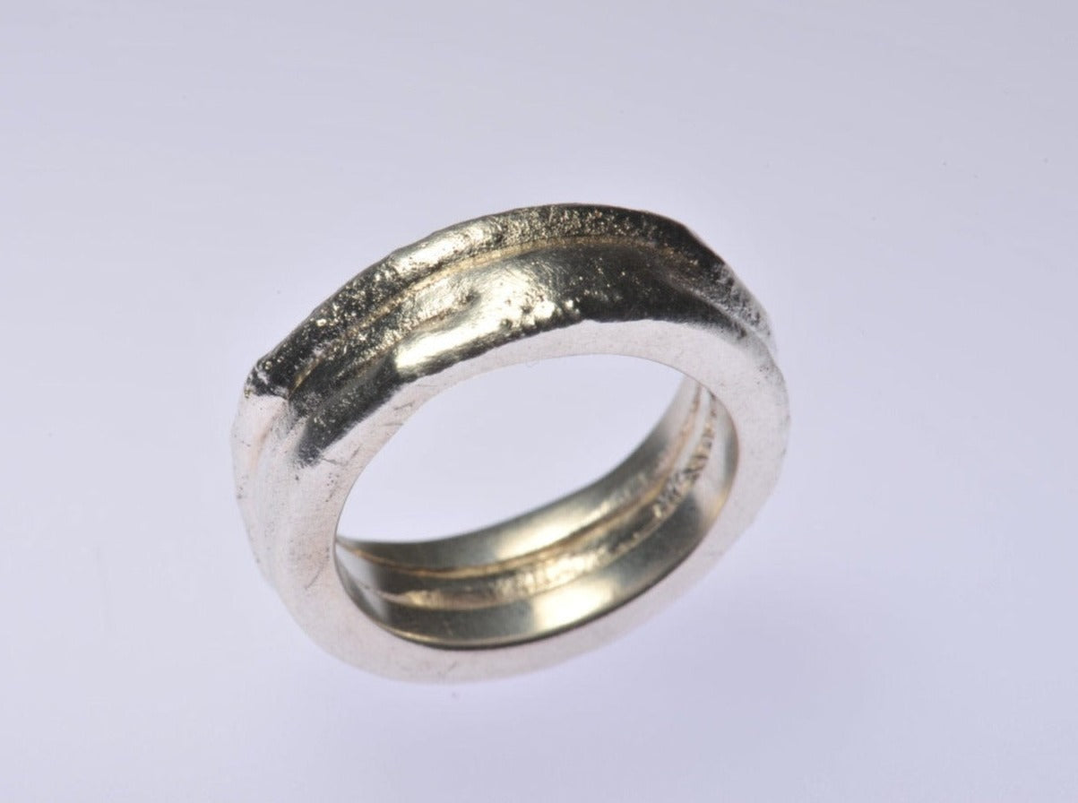 Drei breite Silberbänder, die miteinander verschmolzen sind. Durch den Verschmelzungsprozess schmilzt die Oberfläche des Metalls, wodurch die drei separaten Ringe zu einem einzigen werden. Außerdem erhält die Oberfläche eine erstaunliche Textur, eine eigene Haut. Sitzt wunderschön am Finger. Dies ist ein absolutes Einzelstück. Ringgröße US 9 1/4, UK S 1/2, europäische Größe 21 (61 mm Fingerumfang). Der Ring ist 8 mm breit und 3 mm dick.