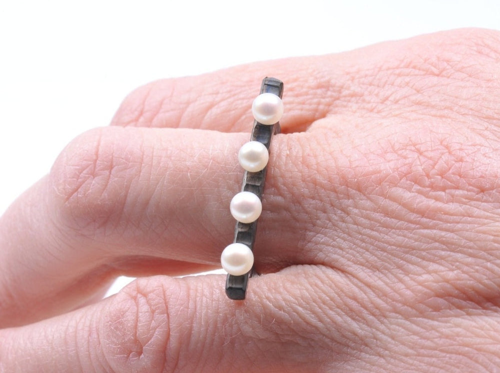 
                  
                    Perlen mit Pfiff. Gehämmertes, oxidiertes Silber kontrastiert mit leuchtend weißen Perlen. Die kontrastierenden Texturen von Perlen und Metall machen diesen Ring zu einem wunderbaren Schmuckstück. 
                  
                