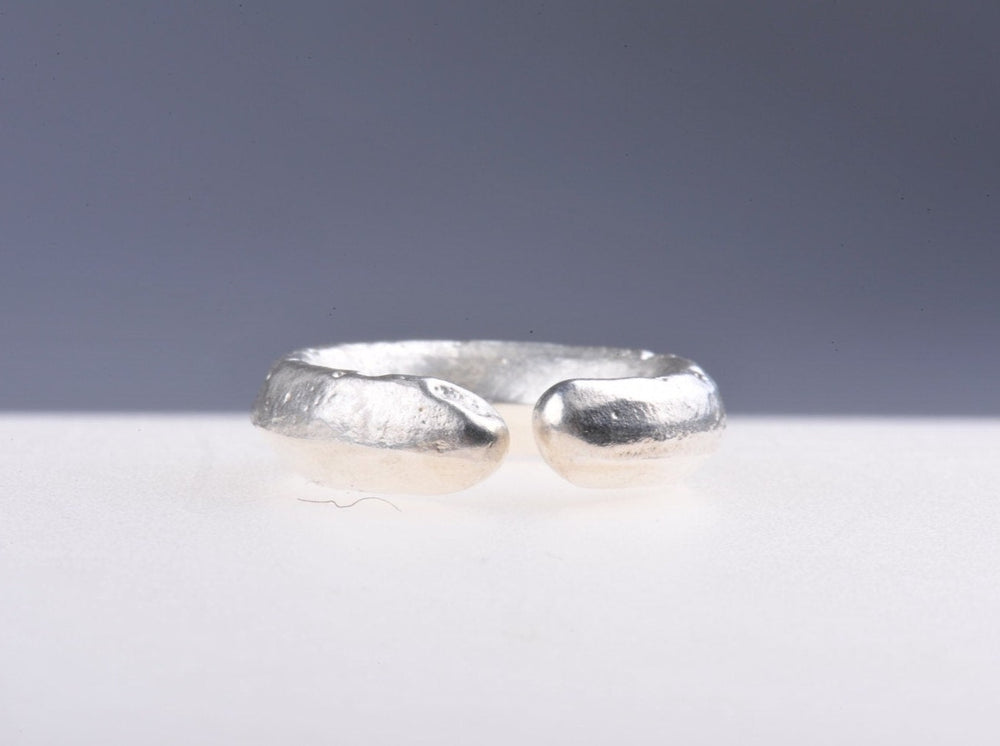 
                  
                    Sand cast, open form recycled silver ring Casting into sand is an ancient technique. The model, in this case a a wax form I had made, is pressed into the sand then removed and the silver is cast into the negative space. A really effective way to recycle old jewellery into something new. This ring has a small gap where the silver stopped, giving a lovely rhythm to the movement of the piece around the finger
                  
                