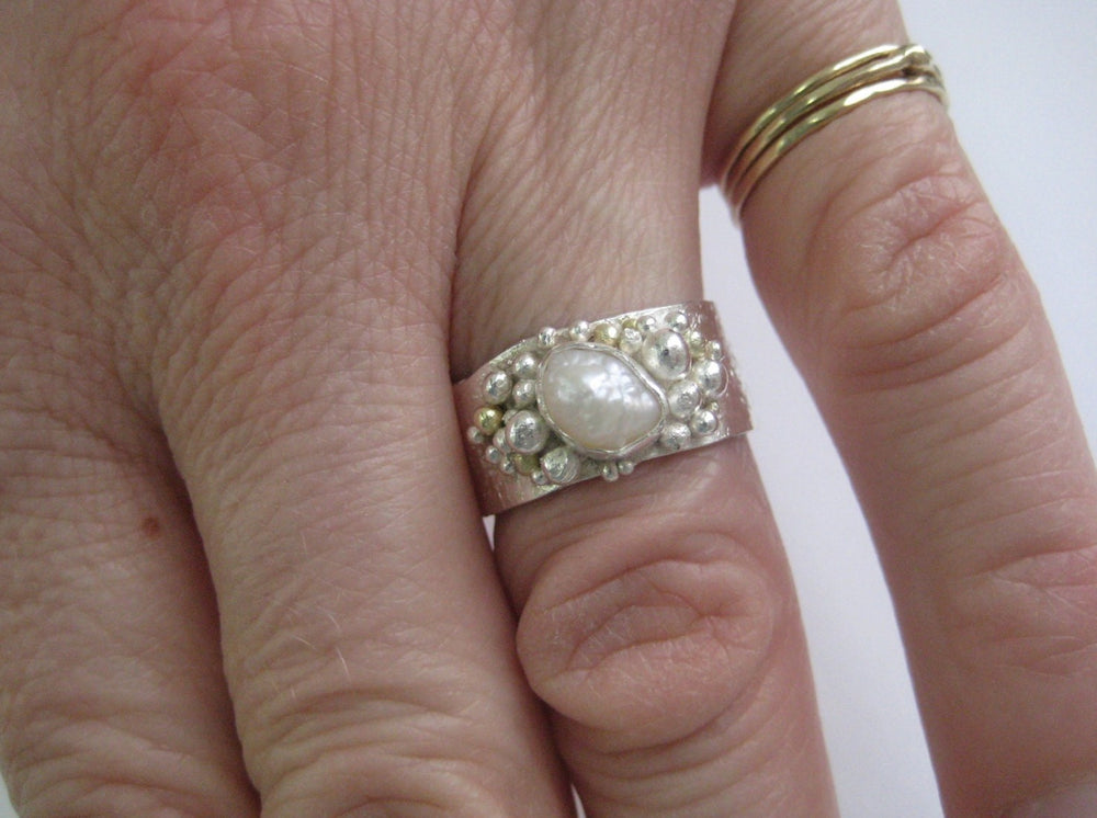 Dieser Ring aus Echtsilber ist mit Gold- und Silberkörnung texturiert. Ich nenne diese Serie meine "Neptun - Ringe", weil sie von den Fingern einer Meerjungfrau stammen könnten.  Der Ring ist 8 -9 mm breit (die Ränder sind nicht gerade, sondern haben sanft geschwungene Kurven) und 1 mm dick. Er ist visuell üppig und gleichzeitig leicht auf dem Finger.